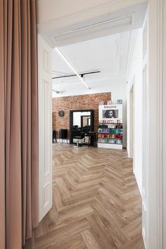 an open room with wooden floors and white walls, along with bookshelves in the background