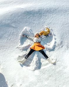 a woman laying in the snow with her arms spread out