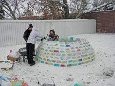 two people standing in the snow next to an ice sculpture with colored glass blocks on it