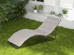 a lawn chair sitting on top of a lush green field next to a house with potted plants