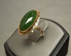 "Vintage Circa 1950 In a Victorian Style Constructed of 10KT Yellow Gold Accented with a Milligrain border & bezel Containing 1 Central Bezel set Genuine Earth-Mined Elongated Oval Piece of Natural Jade measuring approximately 20mm in length x 10mm in width Top section of ring measuring approximately 1\" in length Inside shank: 10K Additional photos/details upon request. Finger Size 6.5 *Sizing upon request (Sizing down runs about $25.. Sizing up starts at $45) Ring weighing 4.5 grams Apprai Estate Style 14k Gold Oval Jewelry, Estate Style Oval Gold Jewelry, Estate Oval Jewelry For Gifts, Vintage Oval Cabochon Jewelry With Bezel Setting, Vintage Oval Jewelry With Bezel Setting, Antique Jade, Elongated Oval, Bezel Ring, Marquise Cut Diamond