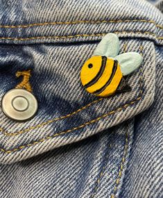 a yellow and black bee pin sitting in the pocket of a blue jean jeans jacket