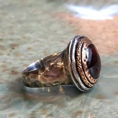 It's got to be This is a stunning ring. The band is slightly hammered. The bezel is made from yellow gold set with a deep red garnet. Garnet is a hard, brilliant stone. It occurs in certain shades of red that have been taken for some varieties of ruby. (R2432). © 2011 - 2016 Artisanimpact Inc. All rights reserved. Construction & Dimensions: Sterling silver, yellow gold, garnet. Approximate width: 16mm (0.68in). We can make any size, including quarter sizes. For this wider band, we suggest ad Silver Gold Ring, Two Tone Ring, Garnet Ring Silver, Red Garnet Ring, Meditation Rings, Gold And Silver Rings, Got To Be, Statement Ring Silver, Yellow Gold Setting