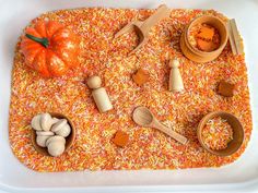 an assortment of wooden utensils and ingredients in a white tray with orange sprinkles