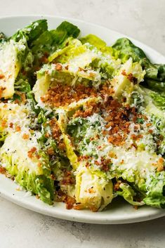 a white plate topped with lettuce covered in parmesan cheese and seasoning