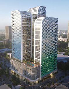 an aerial view of two tall buildings with green and blue designs on the sides, in front of a cityscape