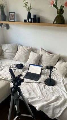 a laptop computer sitting on top of a white couch next to a camera tripod