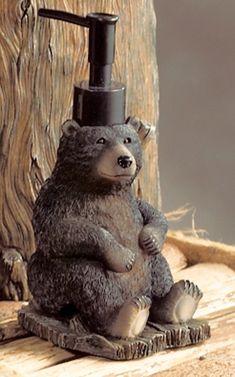 a bear figurine sitting on top of a wooden table next to a soap dispenser