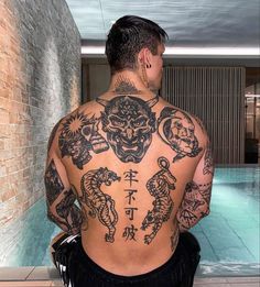 a man with tattoos on his back sitting next to a swimming pool