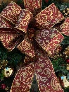 a red and gold christmas bow with ornaments around it