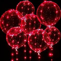 several red balloons with lights on them in the dark