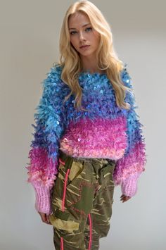 a woman with blonde hair wearing colorful sweater and pants