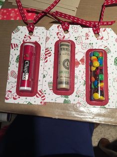 three different types of candy in plastic containers on top of a cardboard box with red ribbon