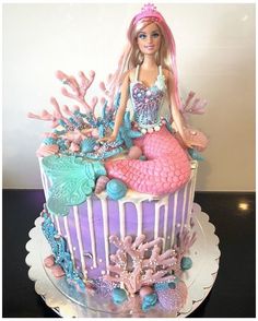 there is a cake that looks like a mermaid on top of the cake with pink and blue decorations