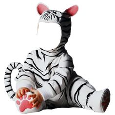 a baby dressed as a zebra sitting on the ground with its paw in his mouth