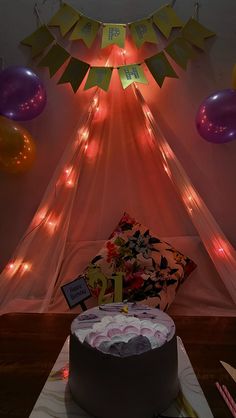 a birthday cake sitting on top of a table next to some balloons and streamers