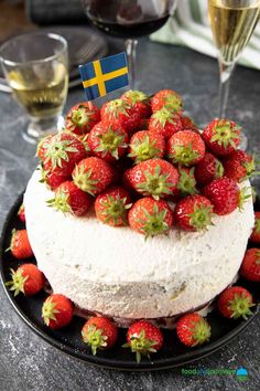 there is a cake with strawberries on it and a glass of wine in the background