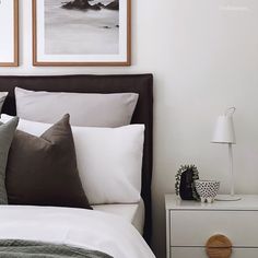 a bed with two framed pictures above it next to a night stand and nightstands