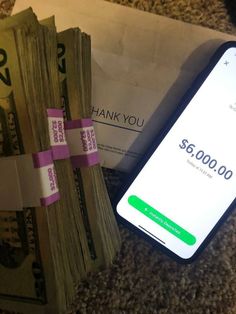 a phone sitting on top of a pile of money next to a stack of cash