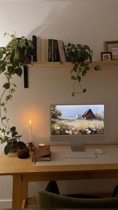 a computer on a desk with a candle and some plants in front of the monitor