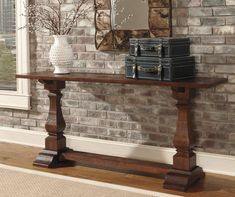 a wooden table sitting in front of a brick wall with a mirror on top of it