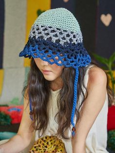 a woman wearing a crocheted hat holding a doughnut