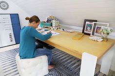 a woman sitting at a desk with pictures on the table and other items in front of her