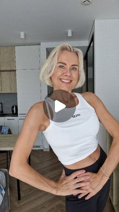 an older woman is posing for the camera with her hands on her hips while wearing black leggings and a white tank top