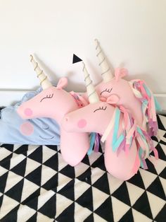 two pink unicorn pillows sitting on top of a black and white checkered floor