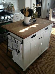 a kitchen island with wooden counter top and white cabinets