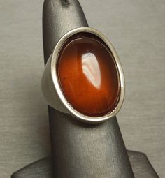 "Vintage Circa 1970 in a Euro Art Deco Style Constructed of Sterling Silver with 1 Oval shaped piece of Natural Amber Top section of ring measuring approximately 1\" in length & about 9.9mm high when on the finger Stamped: 925 Additional photos/details upon request. Finger Size 7.5 *Sizing upon request (Sizing down runs about $25.. Sizing up starts at $45) Weighing 11.4 grams *Sale of ring includes an appraisal certificate for your insurance purposes. All pieces shipped insured via USPS Prio Retro Polished Rings For Formal Events, Retro Formal Rings With Polished Finish, Retro Rings With Polished Finish For Formal Occasions, Modernist Formal Cabochon Rings, Mid-century Polished Formal Jewelry, Vintage Brown Ring With Polished Finish, Vintage Concave Jewelry With Polished Finish, Modernist Oval Rings For Formal Events, Modernist Oval Rings For Formal Occasions