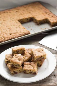 a white plate topped with brownies next to a cookie sheet