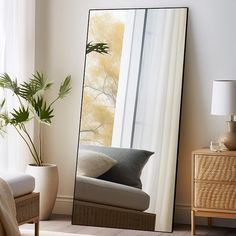 a large mirror sitting on top of a wooden floor next to a chair and potted plant