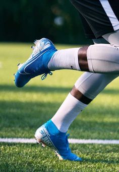 a soccer player with his foot on the ball during a game in blue and white