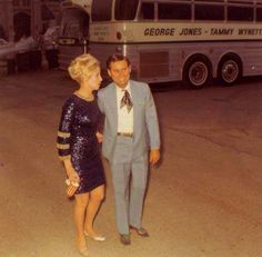 a man and woman standing in front of a bus