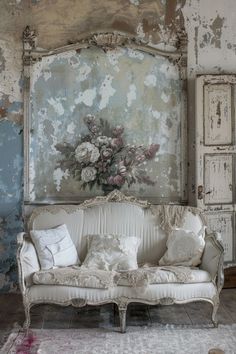 an old couch with flowers painted on the wall behind it in a room that has peeling paint