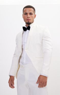 DETAILS This white tailored fit tuxedo is a unique and stylish option for any special or formal event. Features a raised laced texture of the fabric that creates depth and dimension, adding a tactile element to the jacket. Designed with a mandarin collar. which adds a touch of modernity to the jacket. As well as having a satin finish around the closure, giving a luxurious sheen to the outfit. Pair with any Tomson Tuxedo Pants SIZE + FIT Tailored fit, to find your correct size use the ''What's my Elegant Spring Ceremony Suits, White Spring Party Suits, Luxury Fitted Blazer For Ceremonies, White Fitted Tuxedo For Ceremony, White Tailored Suits For Ceremony, White Fitted Blazer For Ceremony, White Spring Wedding Tuxedo, Luxury Spring Wedding Suits, Tailored Tuxedo Blazer For Ceremonies