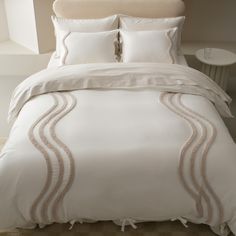 a bed with white sheets and pillows in a hotel room or apartment building, close up on the comforter