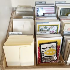 many cards and envelopes are on display in a cabinet with labels for each card