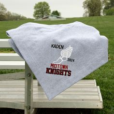 a towel is sitting on a bench in front of a field with trees and grass