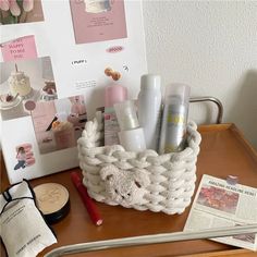 the contents of a white basket on a wooden table next to a magazine and other items