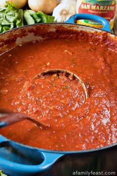 a blue pot filled with sauce next to vegetables