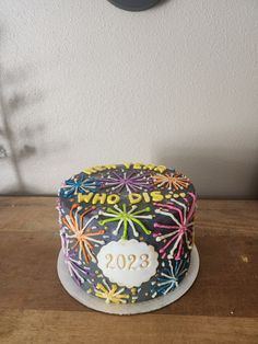 a decorated birthday cake sitting on top of a wooden table in front of a clock