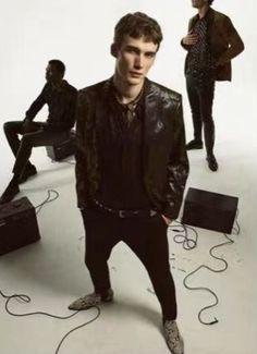 a man standing in front of a group of men with guitars and amps on the floor