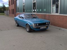 a blue car parked in front of a brick building