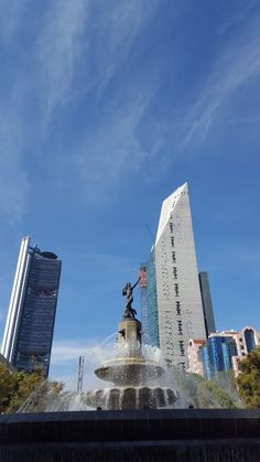 a fountain in the middle of a city with tall buildings behind it