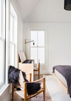 a bedroom with white walls and wooden furniture