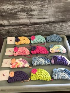 several crocheted mice are displayed on a tray with cards and numbers in front of them