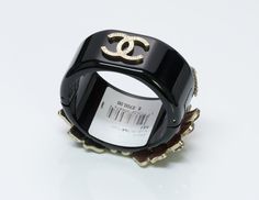 Chanel Gripoix Flower Bangle Bracelet Limited edition Chanel bangle bracelet from Cruise 2015 Dubai Collection. Black bracelet with multi-color Gripoix poured glass flower design on the front and gold tone "CC" logo on the back. Hinged bangle with magnetic clasp and safety chain. Retails at $2700 + Tax. Approximate Measurements: Diameter 2.3”, Width 1.5” Made in: Italy Condition: Excellent Thanks for viewing this item: we have more Chanel jewelry here. To find out more about Chanel's history ple Chanel Bangle, Holiday Raffle, Chanel Items, Genuine Love, Black Bracelet, Chanel Jewelry, Safety Chain, Black Bracelets, Hinged Bangle