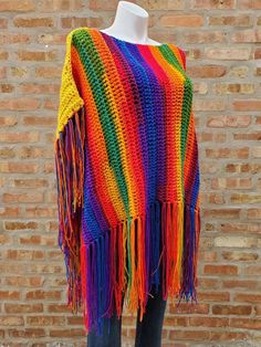 a colorful crocheted shawl on a mannequin's dummy with brick wall in the background